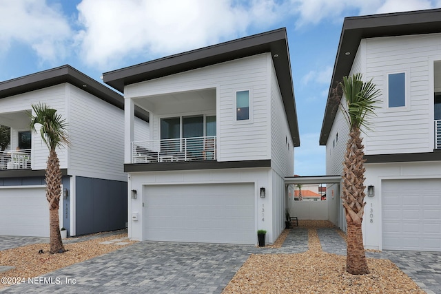 view of front facade featuring decorative driveway, a balcony, and an attached garage