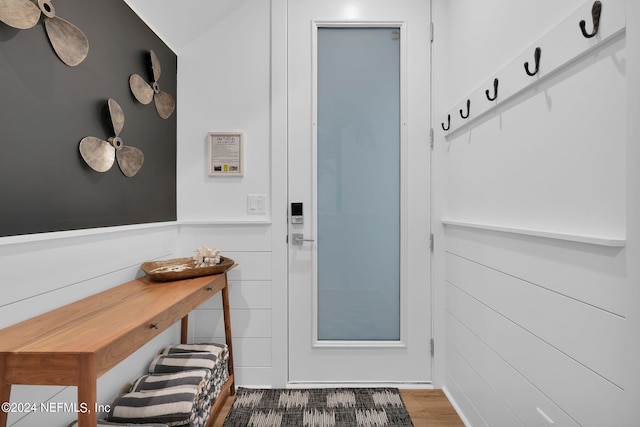 doorway to outside featuring a wainscoted wall and wood finished floors