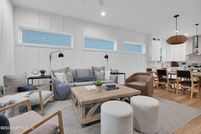 living room featuring recessed lighting, ceiling fan, light wood-style flooring, and a decorative wall