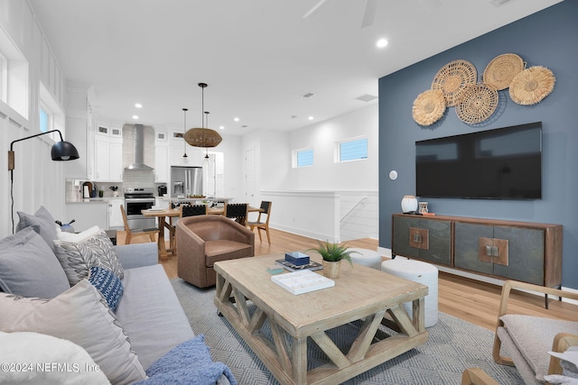 living area featuring plenty of natural light, light wood-type flooring, recessed lighting, and baseboards