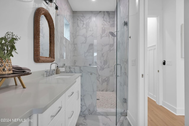 bathroom featuring a marble finish shower, wood finished floors, vanity, and baseboards