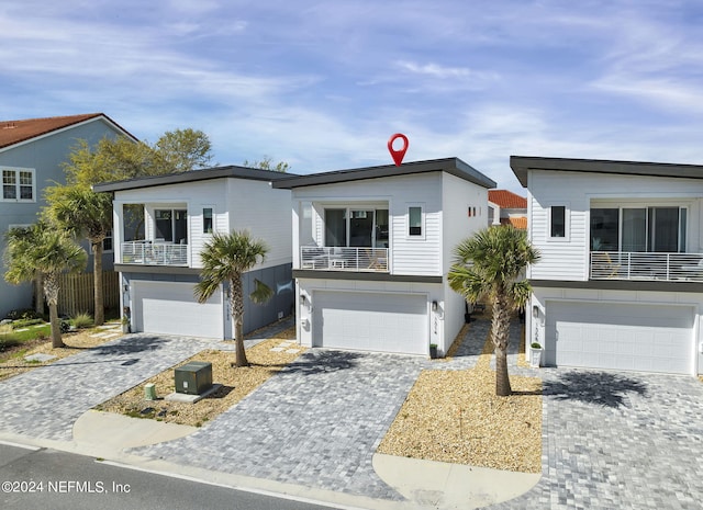 view of front of home featuring decorative driveway, a garage, and a balcony