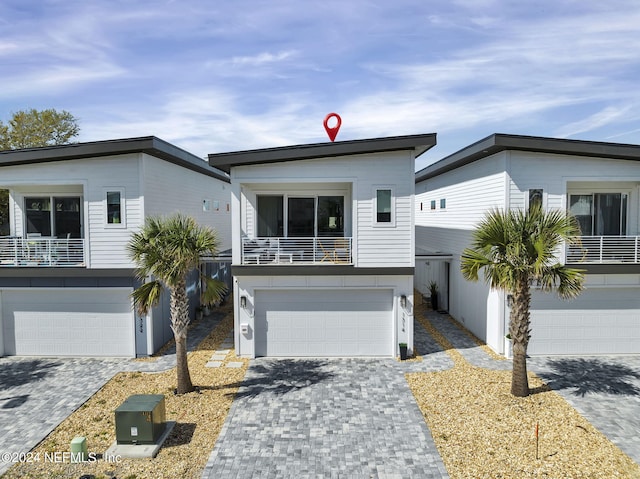 view of front of property with a balcony, decorative driveway, and an attached garage