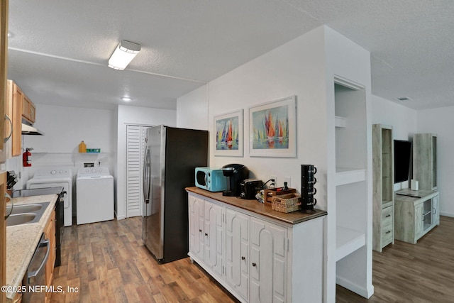 237 Riberia St, Saint Augustine, FL 32084 - kitchen featuring a textured ceiling, appliances with stainless steel finishes, washer and clothes dryer, and wood finished floors