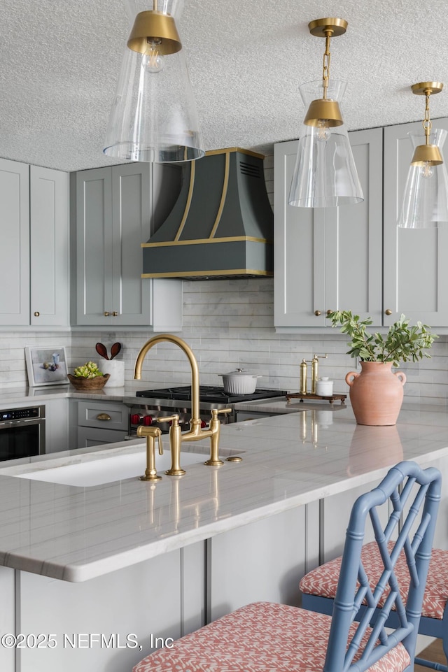 1478 Riverplace Blvd Unit 1008, Jacksonville, FL 32207 - kitchen featuring exhaust hood, a textured ceiling, light stone counters, backsplash, and oven