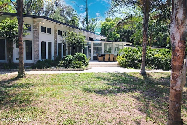 exterior space with a lawn, a sunroom, and brick siding