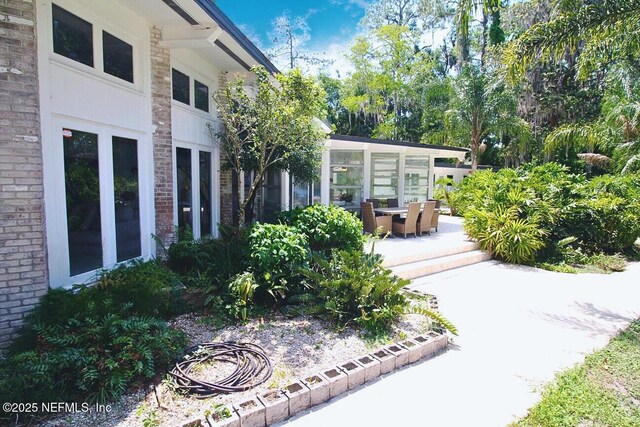 exterior space featuring a patio area, brick siding, and a sunroom