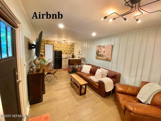 living room featuring light wood-style flooring and a decorative wall