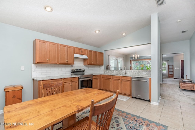 4917 Cypress Links Blvd, Elkton, FL 32033 - kitchen featuring appliances with stainless steel finishes, under cabinet range hood, backsplash, light tile patterned floors, and lofted ceiling