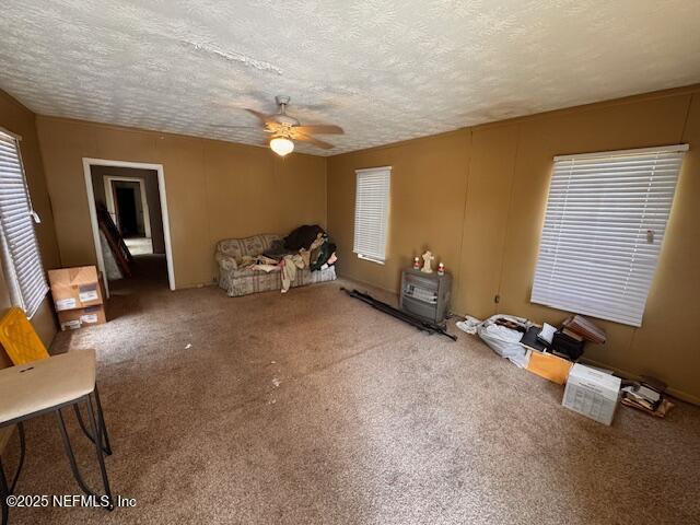 unfurnished living room featuring ceiling fan, a textured ceiling, and carpet flooring