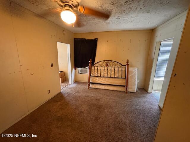 bedroom with cooling unit, a textured ceiling, and carpet flooring