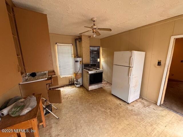 kitchen featuring gas water heater, a ceiling fan, a decorative wall, white appliances, and a textured ceiling