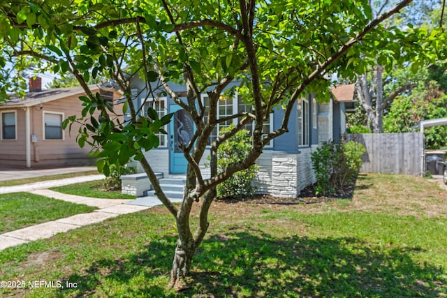 view of front facade featuring fence, entry steps, and a front lawn