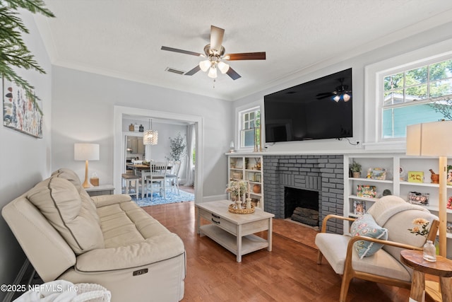 living area with a ceiling fan, plenty of natural light, wood finished floors, and a fireplace