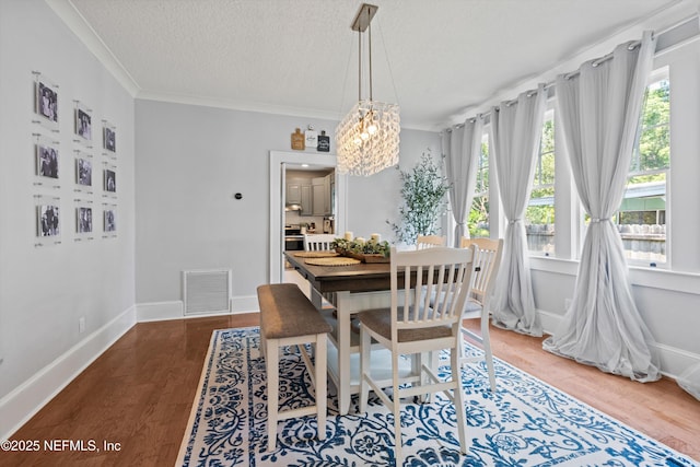 dining room featuring visible vents, wood finished floors, a notable chandelier, and a wealth of natural light