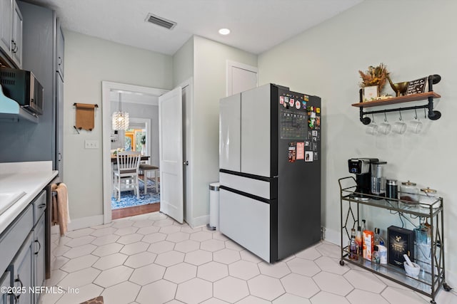 kitchen featuring visible vents, light countertops, freestanding refrigerator, recessed lighting, and gray cabinetry