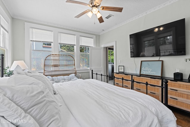bedroom featuring visible vents, ornamental molding, wood finished floors, a textured ceiling, and a ceiling fan