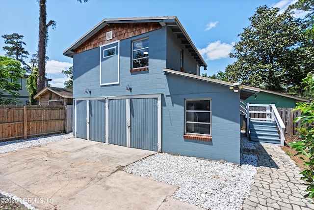 view of property exterior featuring fence, driveway, and concrete block siding