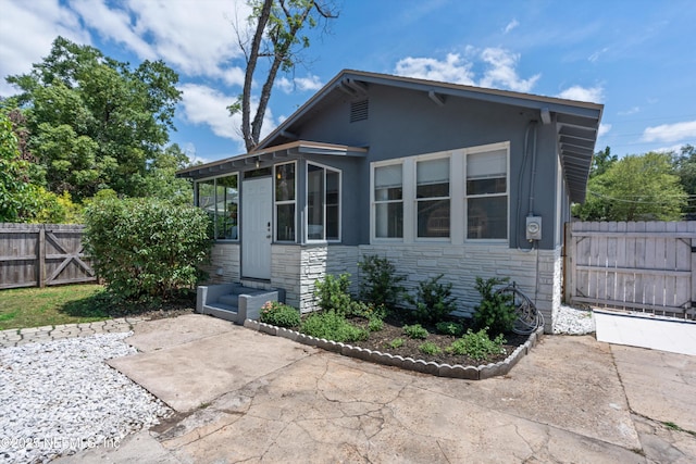 exterior space featuring a patio, fence, stone siding, and stucco siding