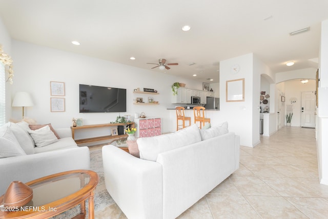 living room featuring light tile patterned floors, ceiling fan, visible vents, arched walkways, and recessed lighting