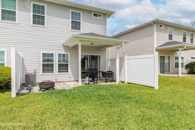 rear view of property featuring a fire pit, fence, a patio, central AC, and a lawn