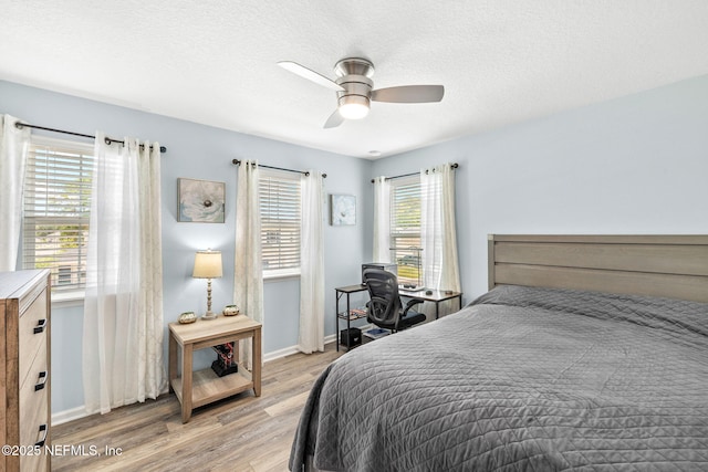 bedroom with light wood-style floors, baseboards, a ceiling fan, and a textured ceiling