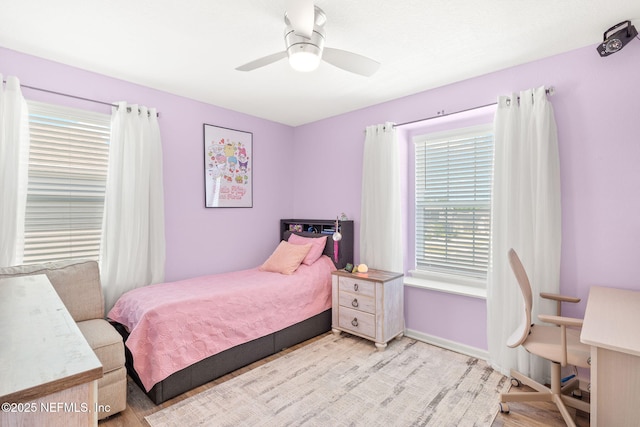 bedroom featuring light wood finished floors, a ceiling fan, and baseboards