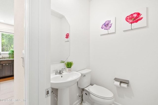 bathroom with toilet, baseboards, and a sink