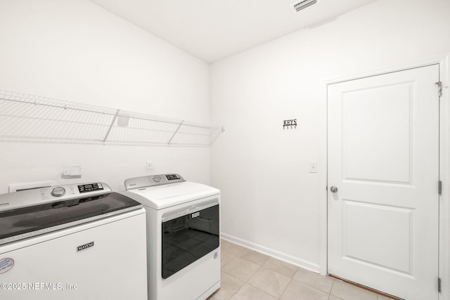 washroom featuring washer and dryer, baseboards, and light tile patterned floors