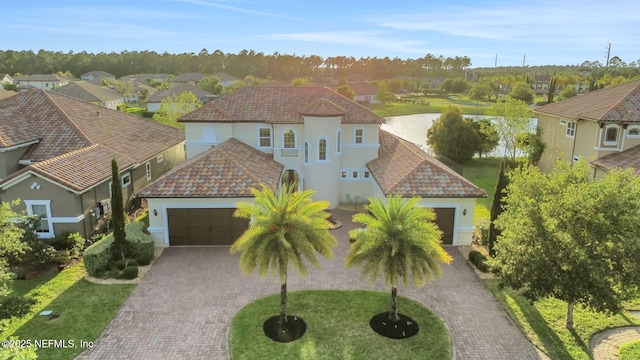 mediterranean / spanish home with a residential view, a garage, stucco siding, and decorative driveway