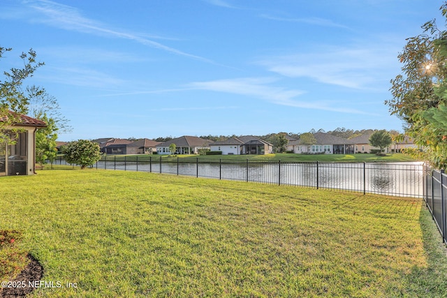 view of yard featuring a fenced backyard, a residential view, and a water view