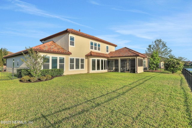 back of property with a sunroom, a lawn, a fenced backyard, and a tiled roof