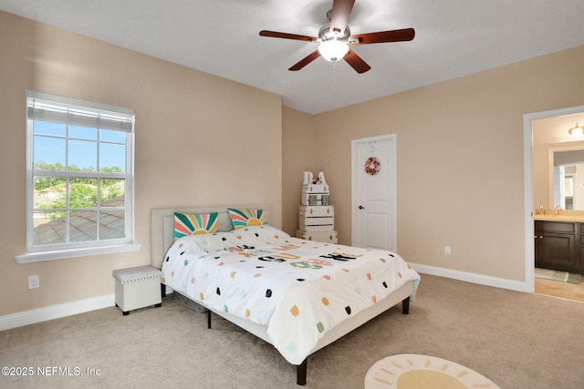 bedroom with baseboards, ceiling fan, light carpet, and ensuite bathroom