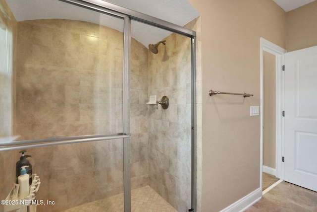 full bathroom with a shower stall and baseboards