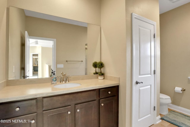bathroom featuring baseboards, toilet, and vanity