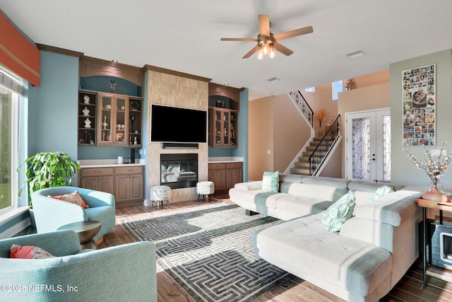 living room with ceiling fan, stairway, wood finished floors, and visible vents