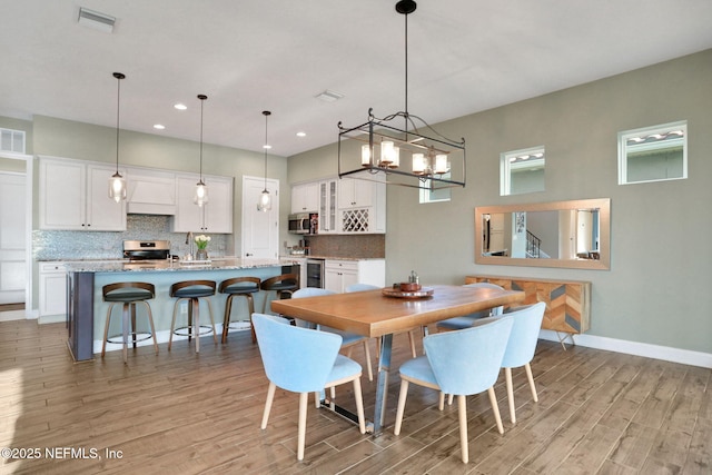 dining room featuring light wood finished floors, recessed lighting, a notable chandelier, visible vents, and baseboards