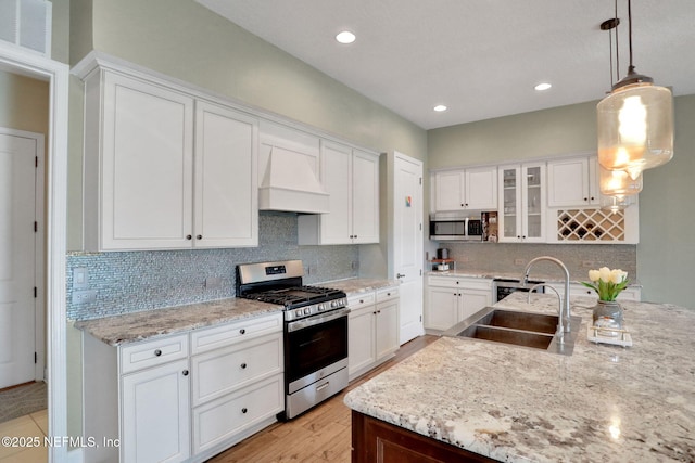 kitchen featuring custom range hood, appliances with stainless steel finishes, a sink, white cabinetry, and visible vents