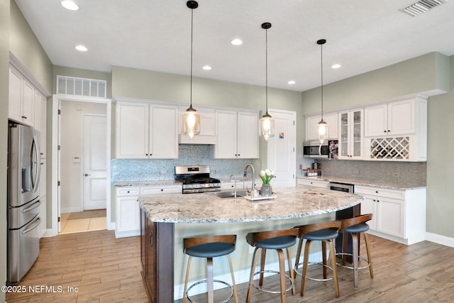 kitchen with visible vents, light wood-style flooring, stainless steel appliances, and white cabinetry