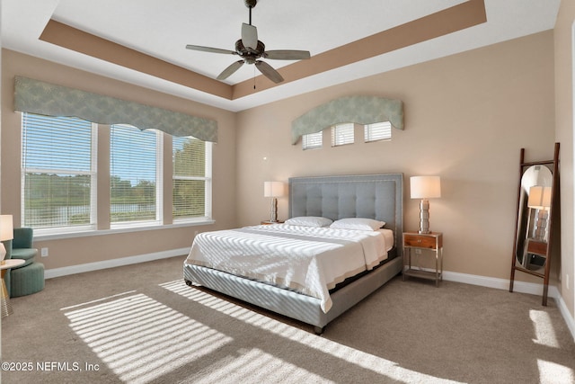 bedroom featuring baseboards, a raised ceiling, a ceiling fan, and carpet floors