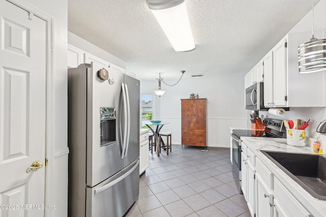 4518 Mountain Brook Ln E, Jacksonville, FL 32224 - kitchen featuring stainless steel appliances, a textured ceiling, white cabinets, pendant lighting, and light tile patterned floors