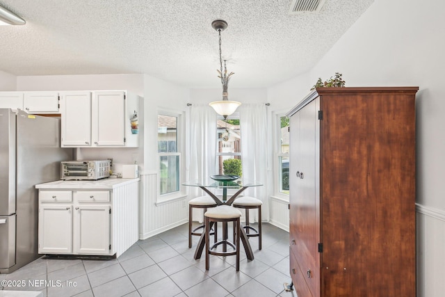 4518 Mountain Brook Ln E, Jacksonville, FL 32224 - kitchen with a textured ceiling, light tile patterned flooring, light countertops, freestanding refrigerator, and white cabinets