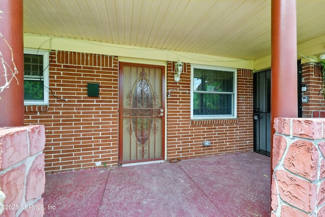 property entrance with covered porch and brick siding