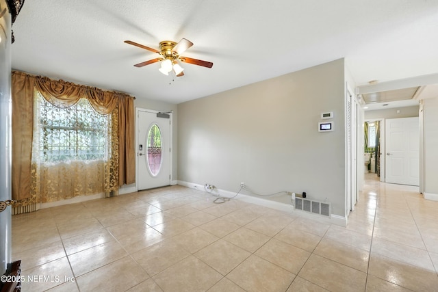 empty room with a healthy amount of sunlight, ceiling fan, light tile patterned flooring, and visible vents