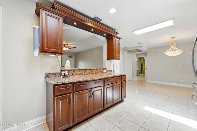 kitchen with visible vents, pendant lighting, light tile patterned flooring, baseboards, and light stone counters