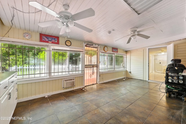 unfurnished sunroom with ceiling fan and a wall mounted air conditioner