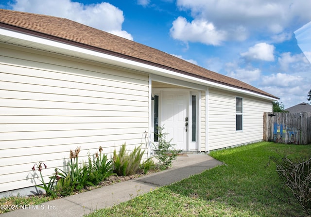 doorway to property with a lawn and fence