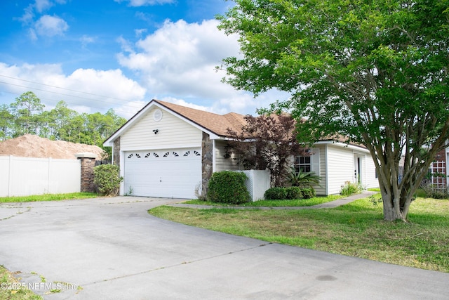 ranch-style house featuring concrete driveway, a front lawn, an attached garage, and fence