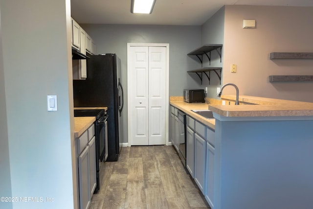 kitchen featuring a sink, under cabinet range hood, open shelves, black appliances, and wood finished floors