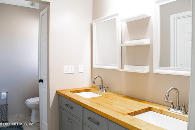 full bath with double vanity, toilet, tile patterned floors, and a sink